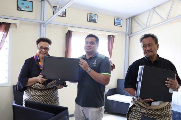 Ministry of Education representatives and ACS holding donated monitors and computers.