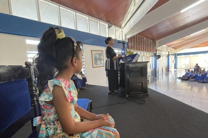 A young girl watching the assembly from the stage.