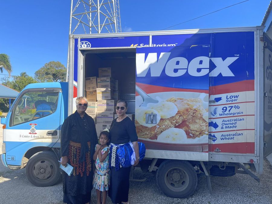 Atiu and Ita with a young girl beside the ACS delivery truck loaded with Weet-Bix and muesli for the breakfast donation.