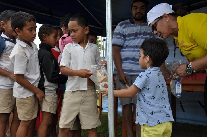 Handing packed lunches to students waiting in line.