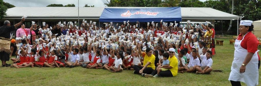 The whole school on the field, every student holding a packed lunch in the air, beneath the Anchor marquee.