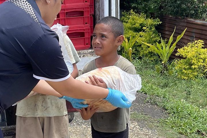 A loaf of bread handed to a young boy at the back of the delivery truck.