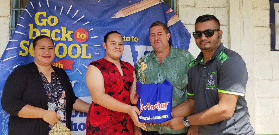 A student and her family receiving a school pack at the Go Back to School banner.
