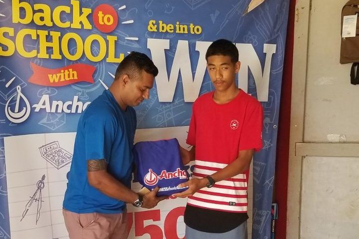 A winner receiving his school pack at the Go Back to School banner.