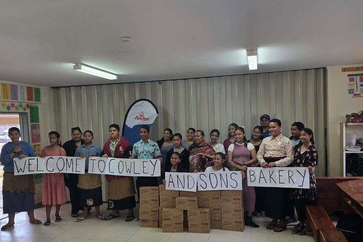 Students holding hand-made signs reading Welcome to Cowley and Sons Bakery.