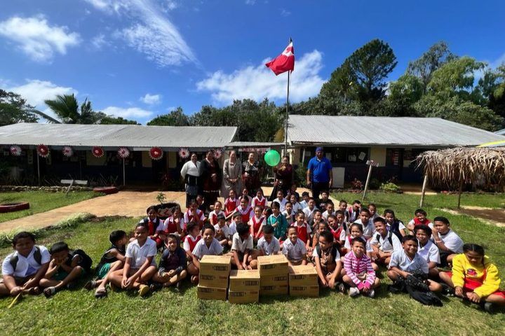 A school gathered under the Tongan flag with their milk boxes.