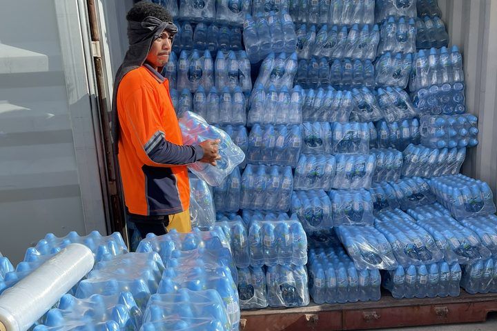 A shipping container packed to the roof with bottled water.
