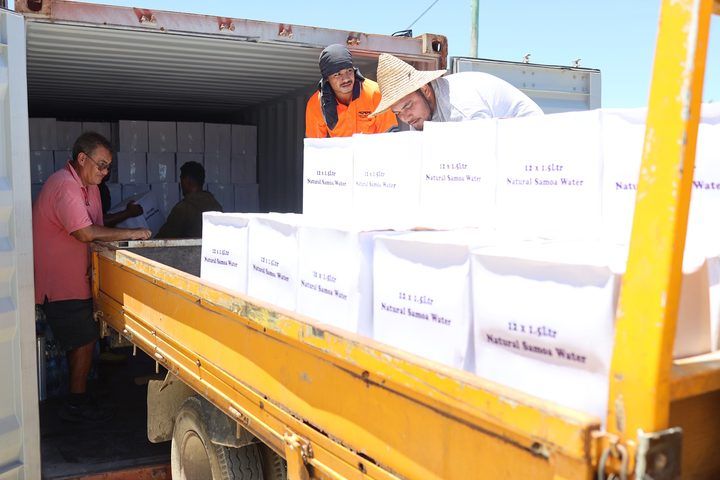 Cartons of Natural Samoa Water being loaded from the container onto a truck.