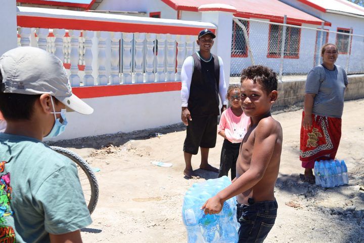 A boy carrying his family’s pack of drinking water home.