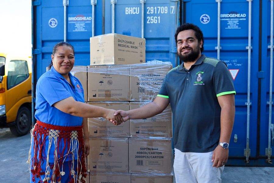 Cartons of disposable medical masks handed over beside the shipping container.