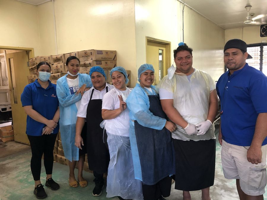 The kitchen team with the delivery, stacked cartons behind them.