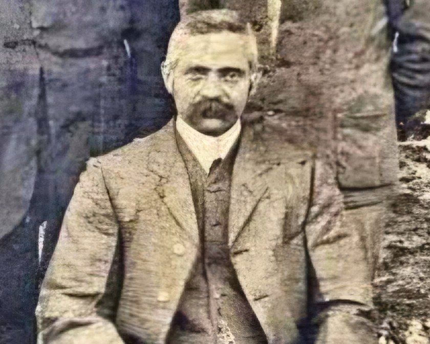 Alfred Cowley, seated, in a three-piece suit with a watch chain.