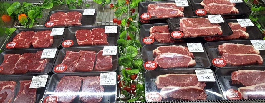Beef scotch fillet and sirloin steaks laid out in the chilled case.