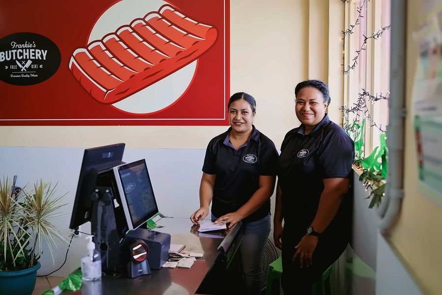 Two Frankie's Butchery staff at the counter, beneath the shop's rack-of-ribs mural.