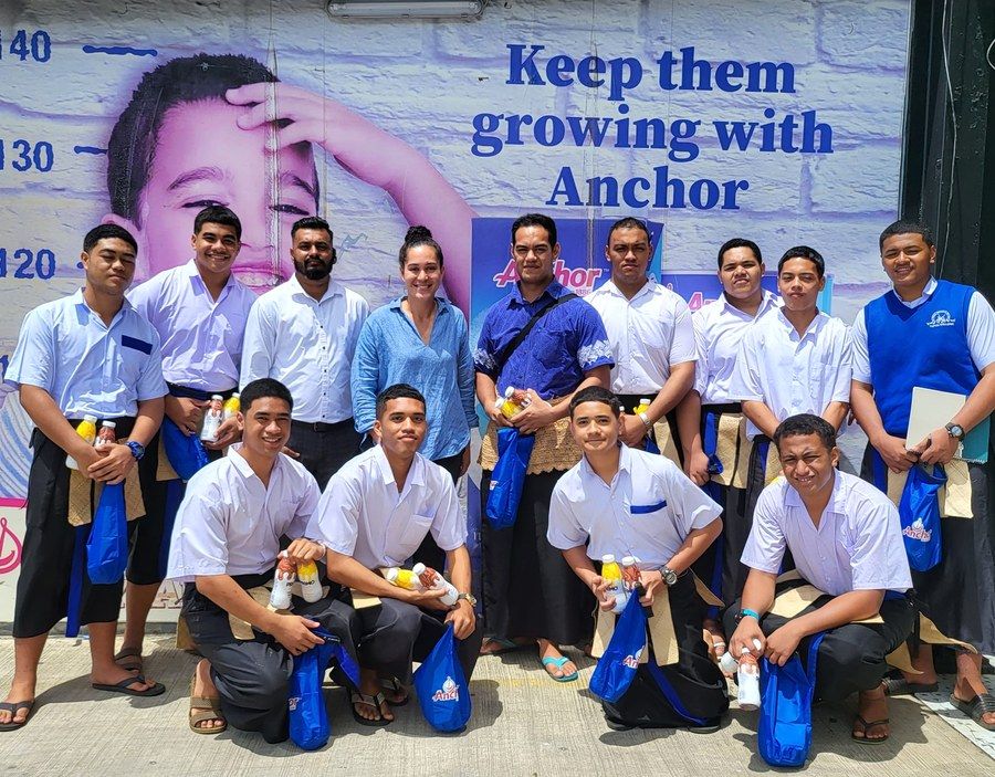 Students and ACS staff at an Anchor school activation beneath a Keep them growing with Anchor mural.