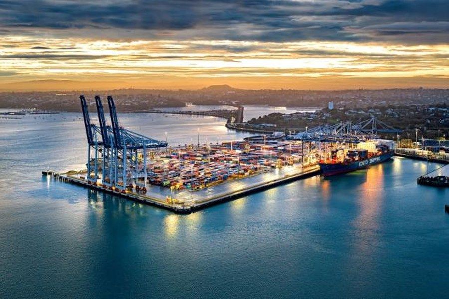 Container terminal at the Ports of Auckland at dusk, with gantry cranes and a vessel alongside.