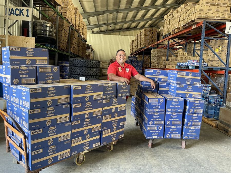 An A. Cowley & Sons staff member with a trolley of cartons in the warehouse, stock ready to go out.